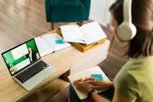 une jeune femme suit des cours en visio sur un ordinateur portable avec un casque sans fi